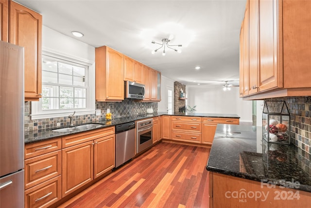 kitchen with sink, backsplash, kitchen peninsula, stainless steel appliances, and dark wood-type flooring