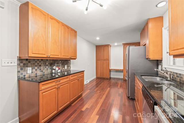 kitchen featuring appliances with stainless steel finishes, sink, backsplash, dark stone counters, and dark wood-type flooring