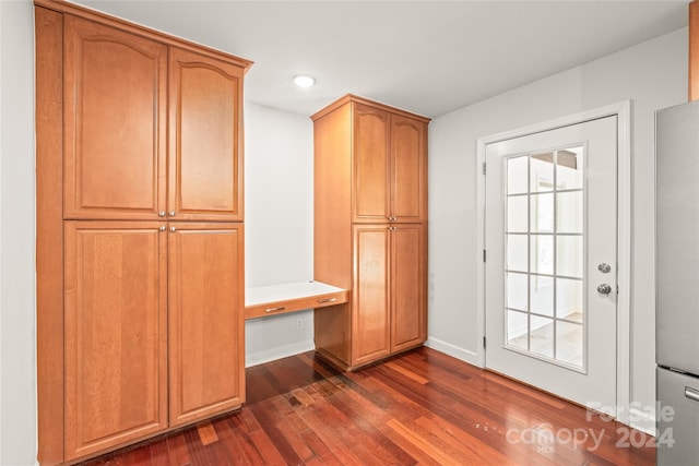 mudroom with built in desk and dark wood-type flooring