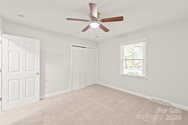 unfurnished bedroom with light carpet, a closet, and ceiling fan