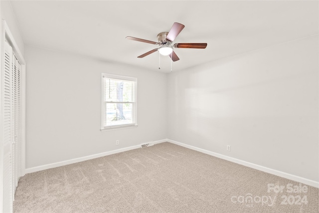 carpeted spare room with ceiling fan