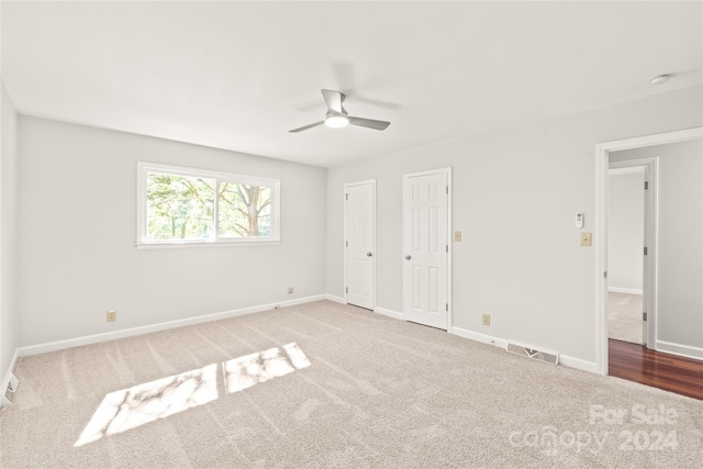 unfurnished bedroom featuring multiple closets, carpet floors, and ceiling fan