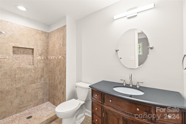 bathroom with vanity, tiled shower, and toilet