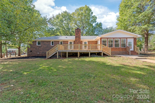 back of property with a wooden deck and a lawn