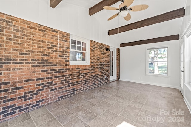 interior space with ceiling fan, brick wall, tile patterned floors, and vaulted ceiling with beams