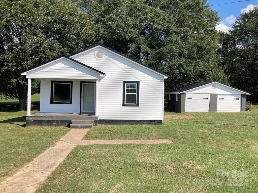 bungalow-style house featuring a front lawn, an outbuilding, and a garage