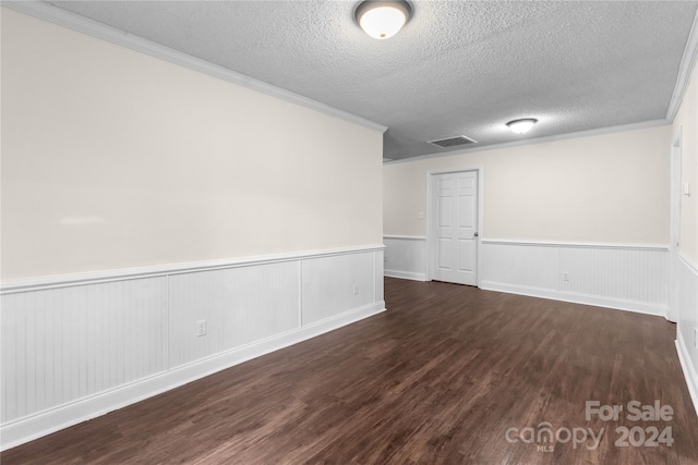 empty room with a textured ceiling, ornamental molding, and dark hardwood / wood-style flooring