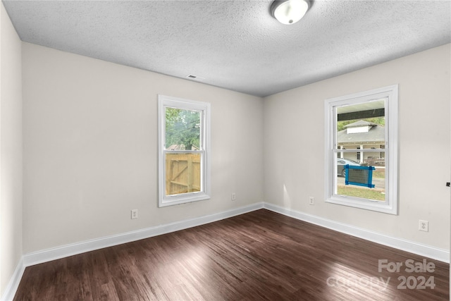 unfurnished room featuring a textured ceiling and dark hardwood / wood-style floors