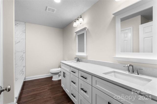 bathroom featuring vanity, a textured ceiling, hardwood / wood-style floors, and toilet