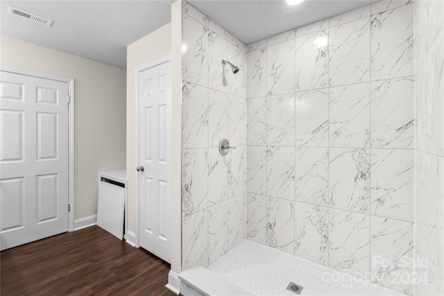 bathroom with a tile shower, vanity, a textured ceiling, and hardwood / wood-style floors