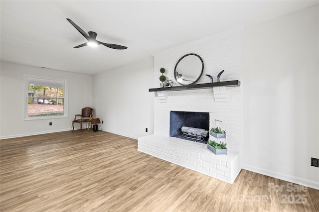 unfurnished living room with light wood-type flooring, a brick fireplace, and ceiling fan