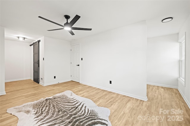 bedroom featuring a barn door, hardwood / wood-style flooring, and ceiling fan