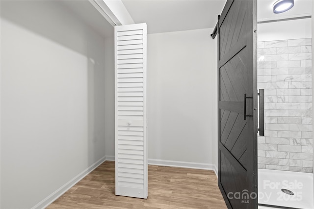 walk in closet featuring a barn door and light hardwood / wood-style flooring