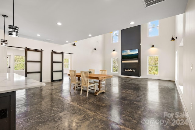 dining room featuring a barn door and a towering ceiling