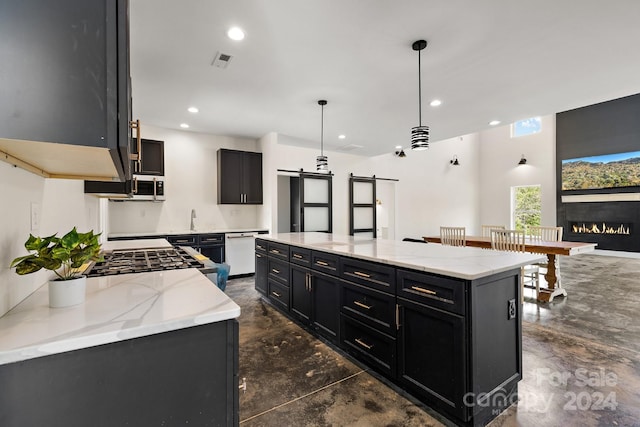 kitchen with light stone counters, a center island, hanging light fixtures, a barn door, and appliances with stainless steel finishes