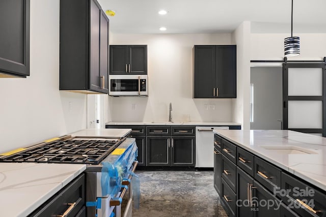 kitchen featuring a barn door, decorative light fixtures, sink, light stone counters, and stainless steel appliances