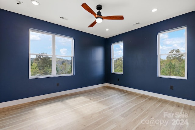 spare room with ceiling fan, light wood-type flooring, and a wealth of natural light