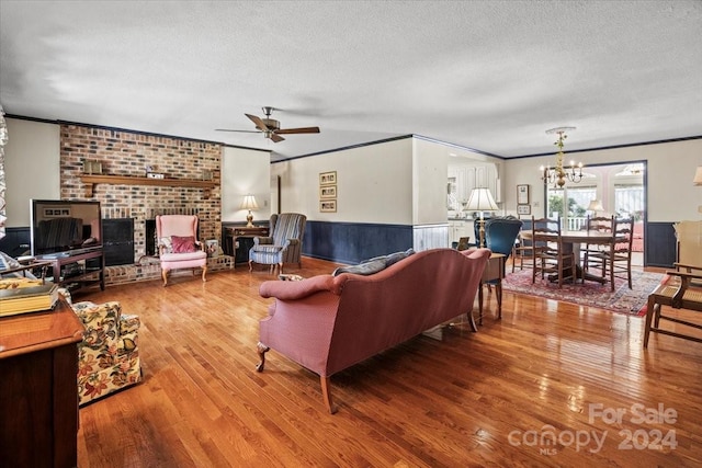 living room featuring ceiling fan with notable chandelier, ornamental molding, hardwood / wood-style flooring, and a textured ceiling