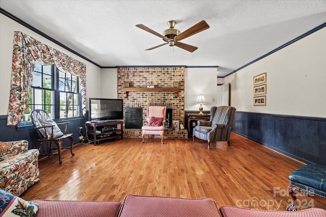 living room featuring crown molding, ceiling fan, hardwood / wood-style floors, and a textured ceiling