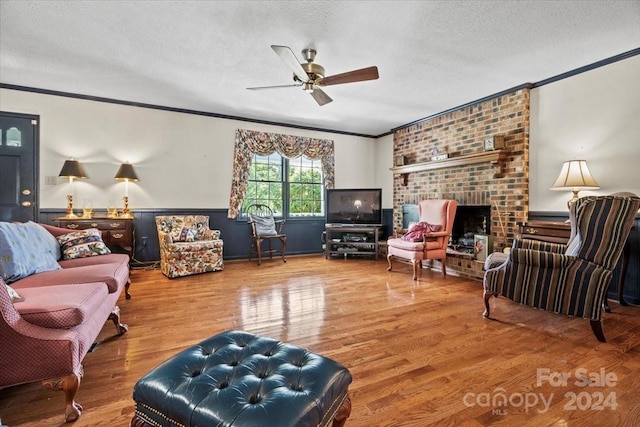 living room featuring ornamental molding, a brick fireplace, hardwood / wood-style floors, and a textured ceiling