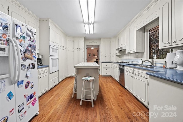 kitchen featuring light hardwood / wood-style floors, white appliances, a kitchen island, sink, and white cabinets