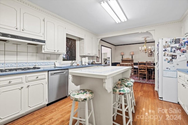 kitchen with stainless steel appliances, white cabinets, a breakfast bar, light hardwood / wood-style floors, and crown molding