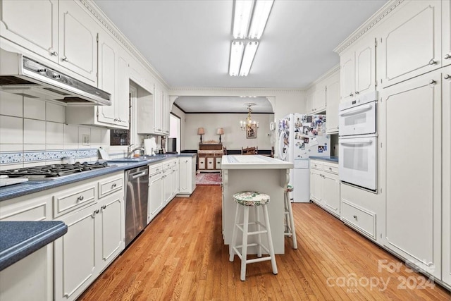 kitchen with stainless steel appliances, decorative light fixtures, light hardwood / wood-style flooring, and a center island