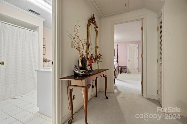 corridor featuring light carpet, a textured ceiling, and ornamental molding