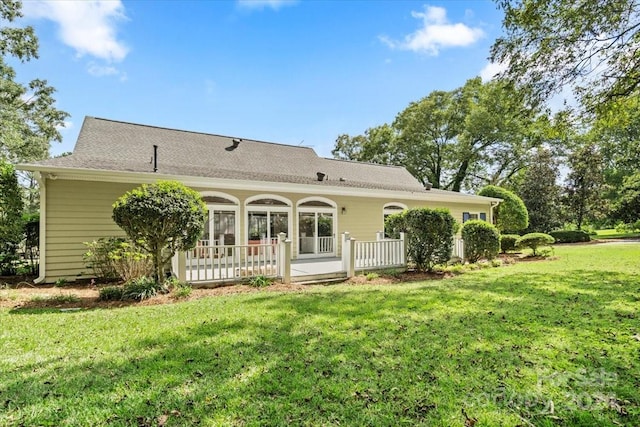 rear view of property with a wooden deck and a yard