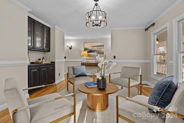 living area with crown molding, light hardwood / wood-style floors, and an inviting chandelier