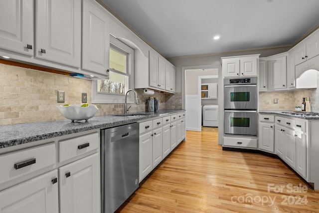 kitchen featuring white cabinets, sink, decorative backsplash, light wood-type flooring, and stainless steel appliances