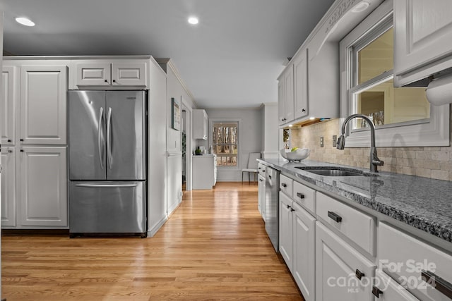 kitchen featuring light stone countertops, stainless steel appliances, sink, light hardwood / wood-style flooring, and white cabinetry