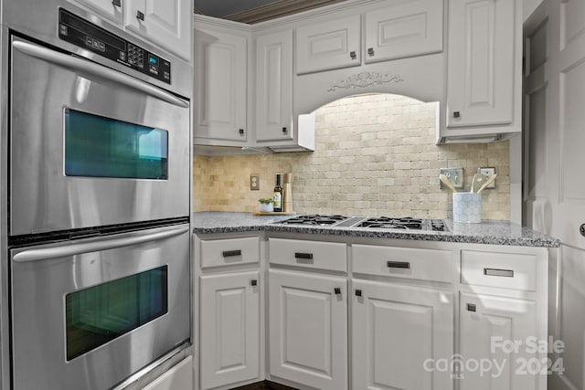 kitchen featuring light stone countertops, decorative backsplash, white cabinetry, and stainless steel appliances