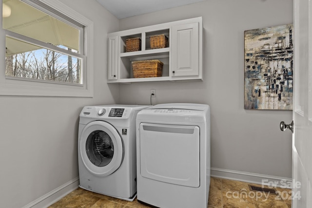 laundry room featuring washer and clothes dryer and cabinets