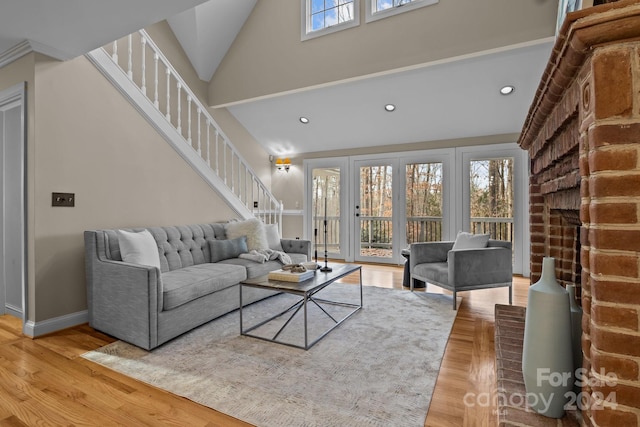 living room with a brick fireplace, light hardwood / wood-style flooring, high vaulted ceiling, and plenty of natural light