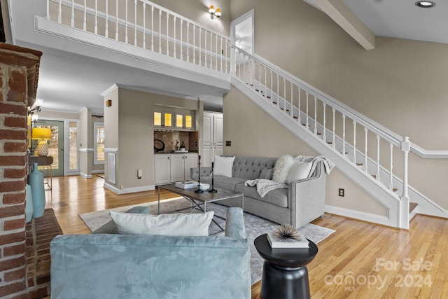 living room with beamed ceiling, high vaulted ceiling, and light hardwood / wood-style flooring