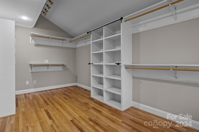 walk in closet featuring hardwood / wood-style floors and vaulted ceiling