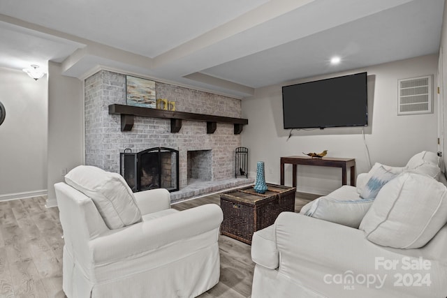 living room with a brick fireplace and light hardwood / wood-style flooring