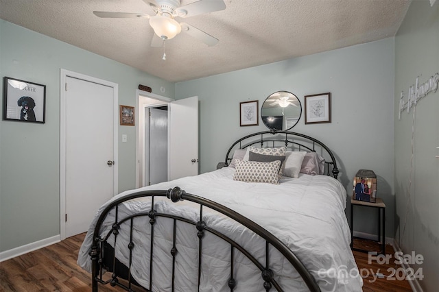 bedroom featuring dark wood-type flooring, a textured ceiling, and ceiling fan