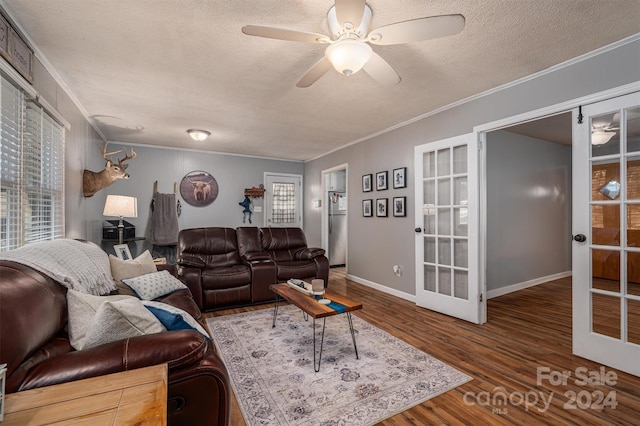 living room featuring ceiling fan, ornamental molding, french doors, a textured ceiling, and dark wood-type flooring