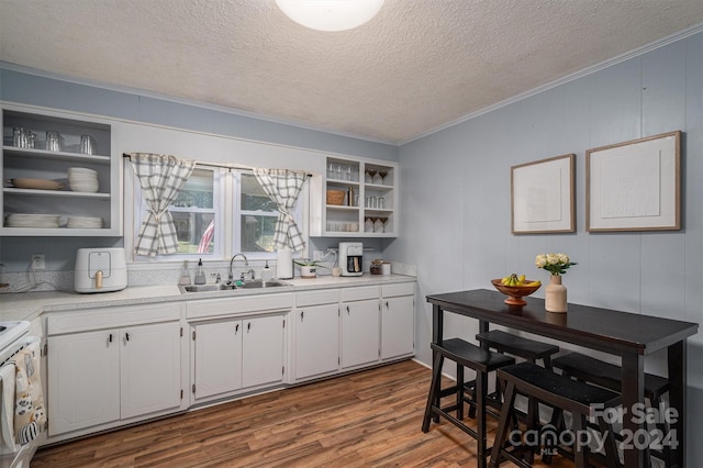 kitchen featuring wood-type flooring, white cabinets, sink, ornamental molding, and white range