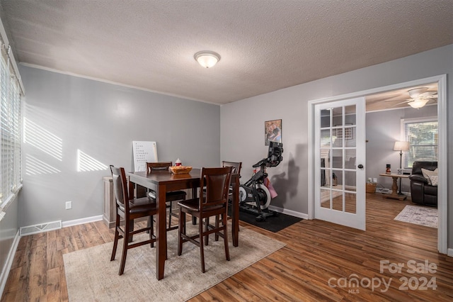 dining room featuring hardwood / wood-style flooring, ceiling fan, and a textured ceiling