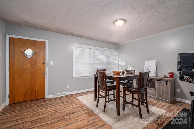 dining area with hardwood / wood-style floors and a textured ceiling