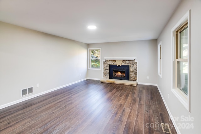 unfurnished living room with dark hardwood / wood-style flooring and a stone fireplace