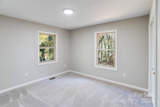 unfurnished room with a wealth of natural light and light colored carpet