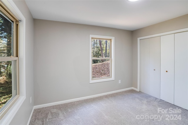 unfurnished bedroom featuring light colored carpet and a closet