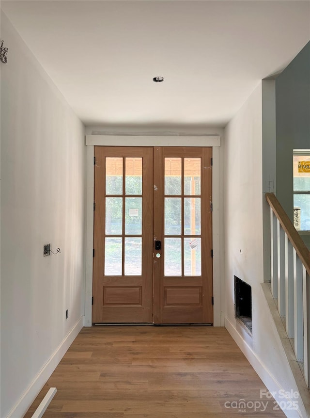 doorway to outside featuring french doors, light wood-type flooring, and baseboards