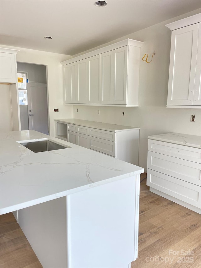 kitchen featuring light wood finished floors, white cabinets, and light stone countertops