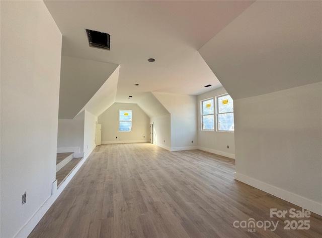 bonus room with a wealth of natural light, lofted ceiling, baseboards, and wood finished floors