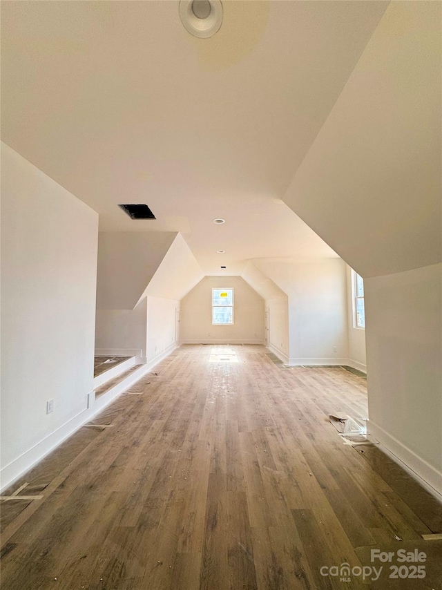 additional living space with baseboards, lofted ceiling, and wood finished floors